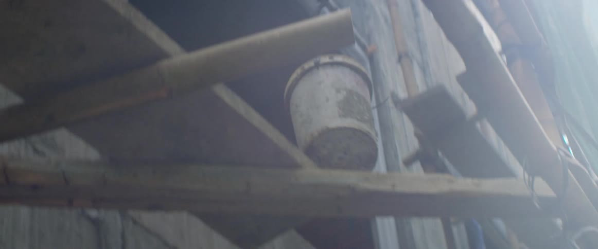 A bucket being raising by rope up through the scaffolding on the outside of a building