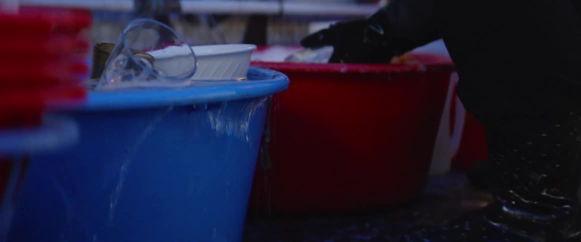 A person washes dishes in buckets