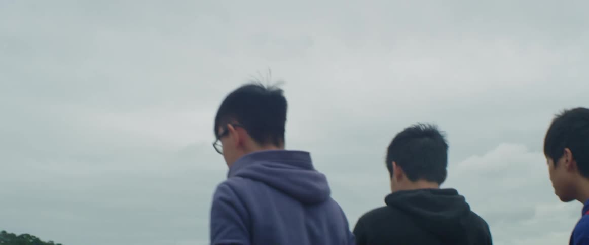 Group of asian teenagers stand near a lake in front of the city