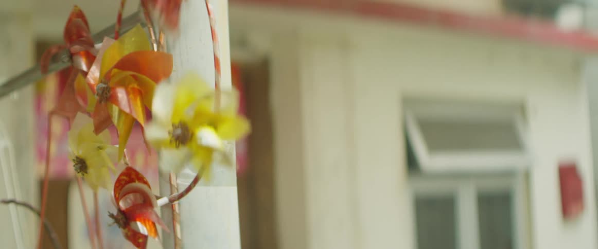Pinwheels whirl while hanging near porch column