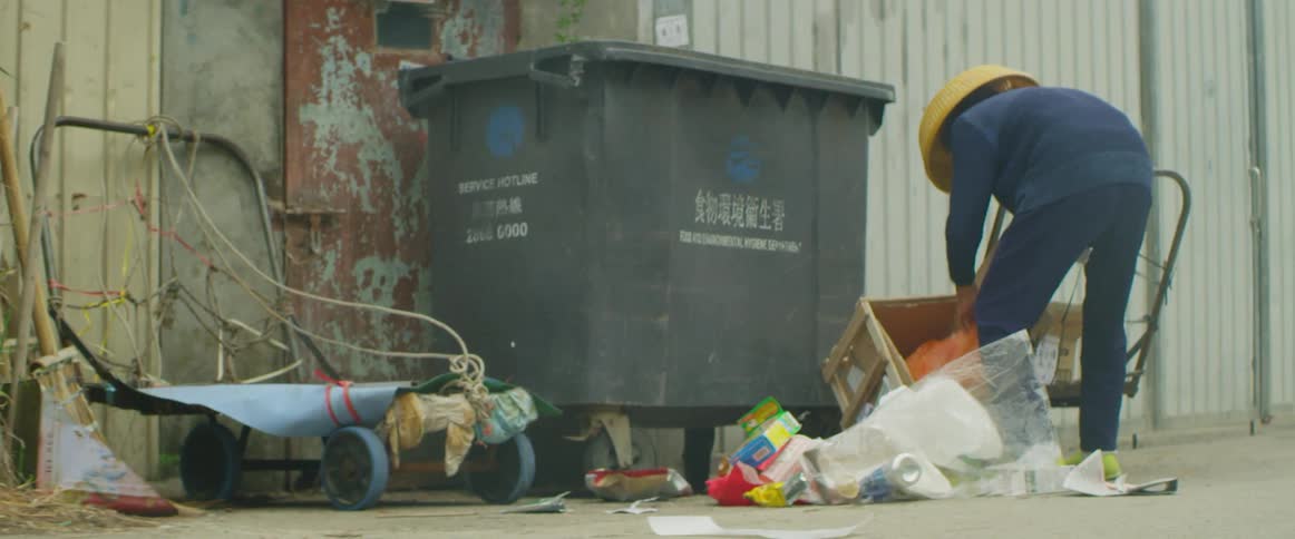Person digs through garbage bins in an alleyway