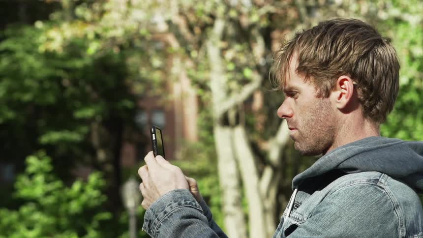 A man raising a smartphone while standing outdoors