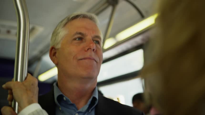 Man rides a bus standing holding a bar