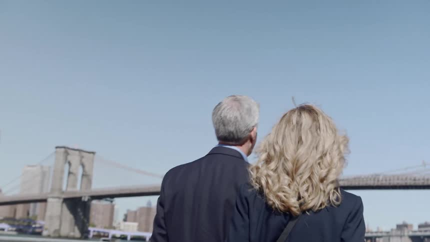 A man and woman walk by a city river