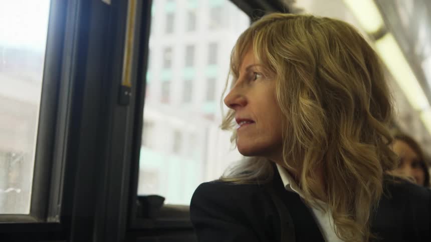 A woman sits on a subway and looks out the window
