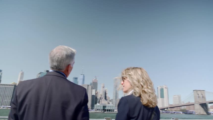 A man and woman talking while looking out over the ocean in a city