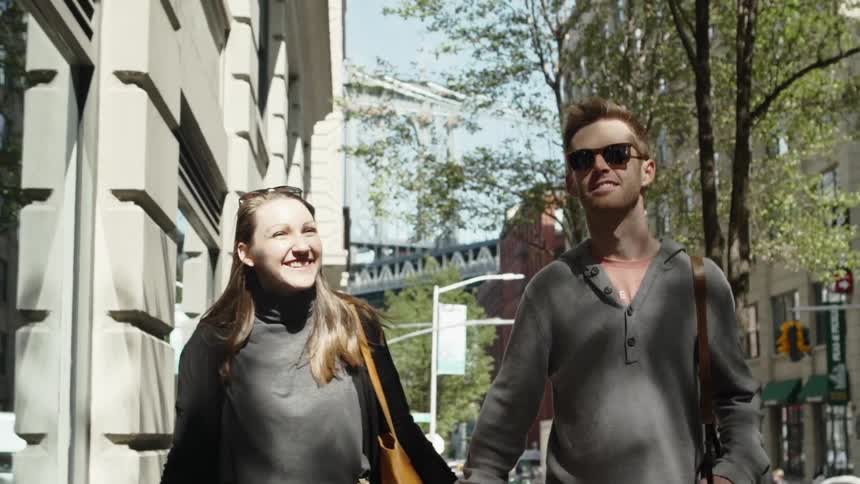 Couple walk along sidewalk holding hands