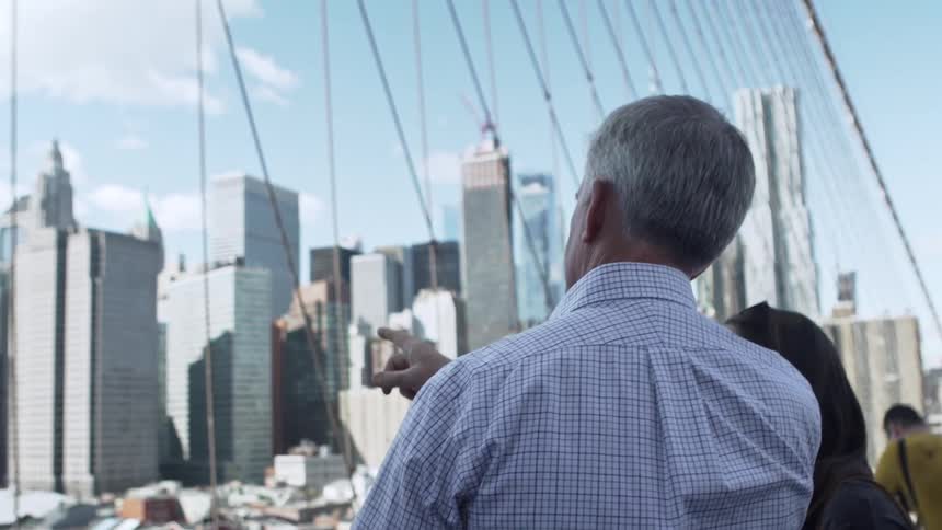 A man points at the city skyline as he talks with a woman