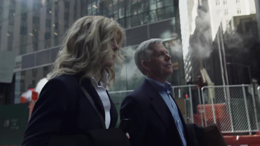 Man and woman in business suits walking down the street in city downtown