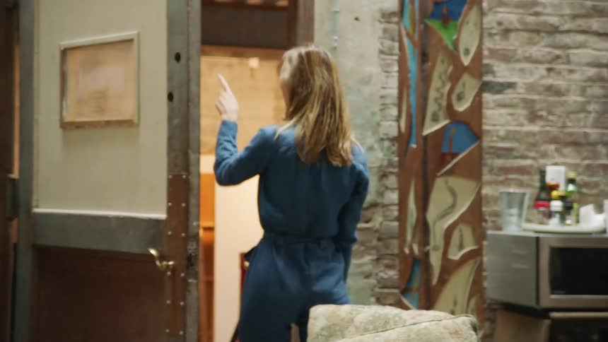 People cross room past microwave and brick wall