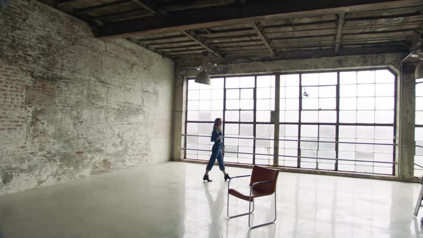 Woman with camera walks through industrial studio loft