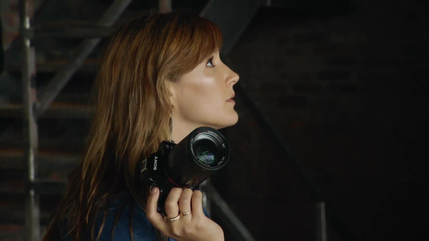 A photographer holds her camera as she talks to someone