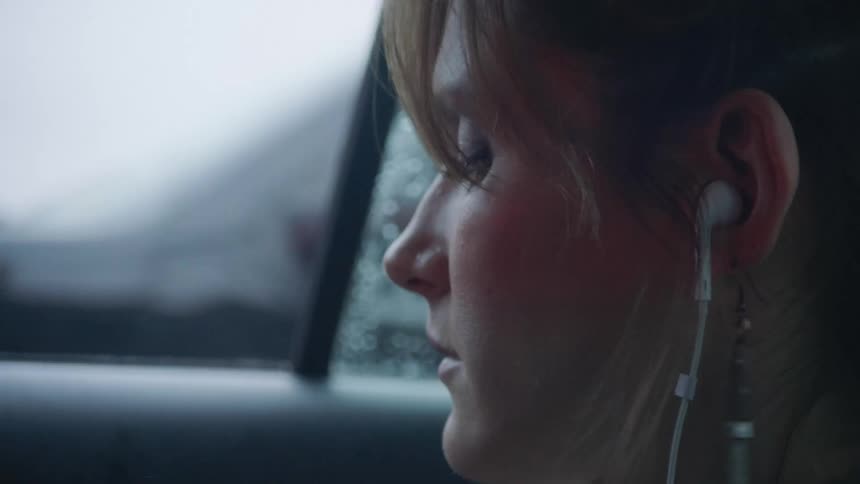 Woman sits in car listening to music on busy street