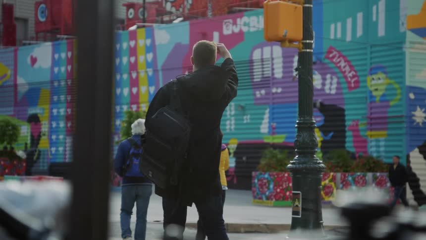 People walking on a city street with a mural in the background