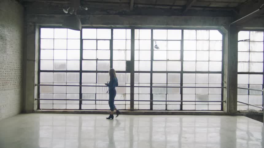 A white woman walks across a spartan room
