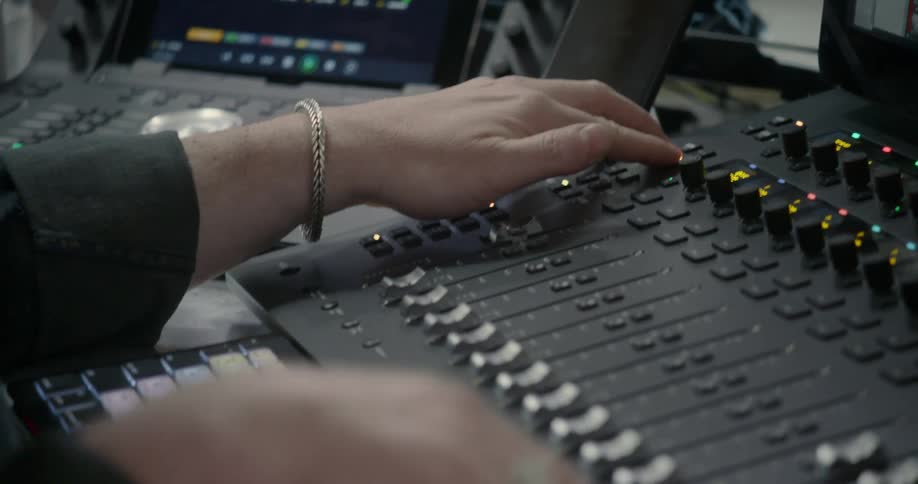 Hands working on sound mixing equipment