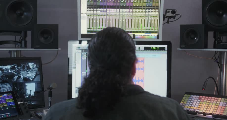 A man in a studio sits in front of a computer and other equipment