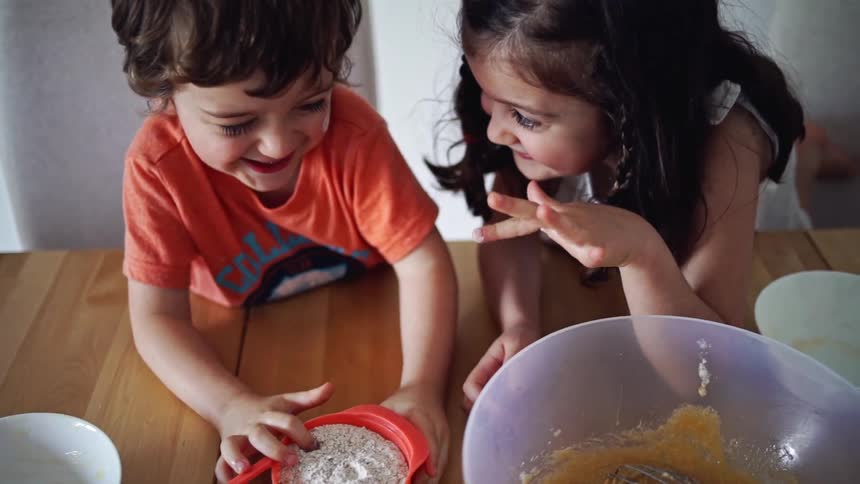 Young siblings playing while helping make food