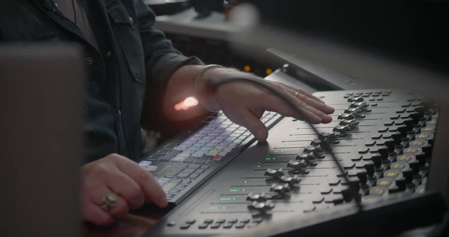 A music producer moves controls on a mixing rack