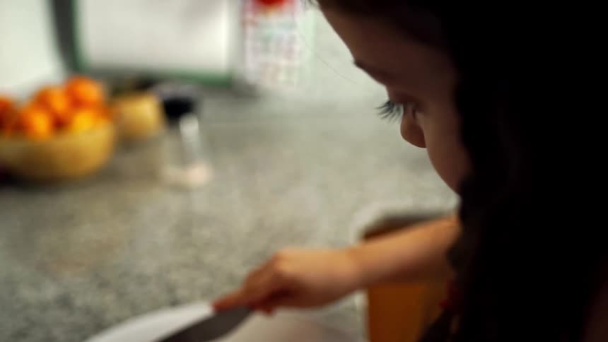 Young girl cuts up food on kitchen countertop
