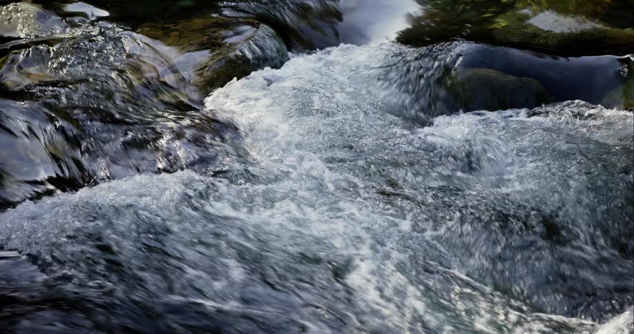 Water flows down sloping riverbed forming rapids