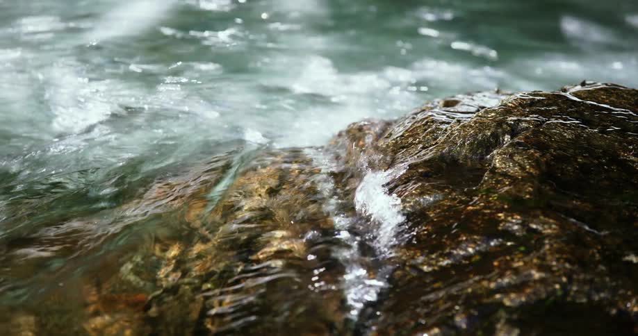 River water breaks against a rock