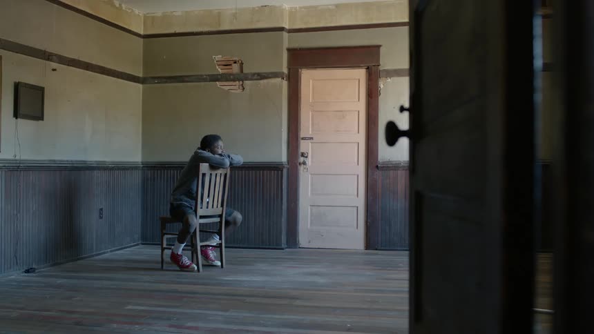 Young man sits in a chair in a room of an abandoned house