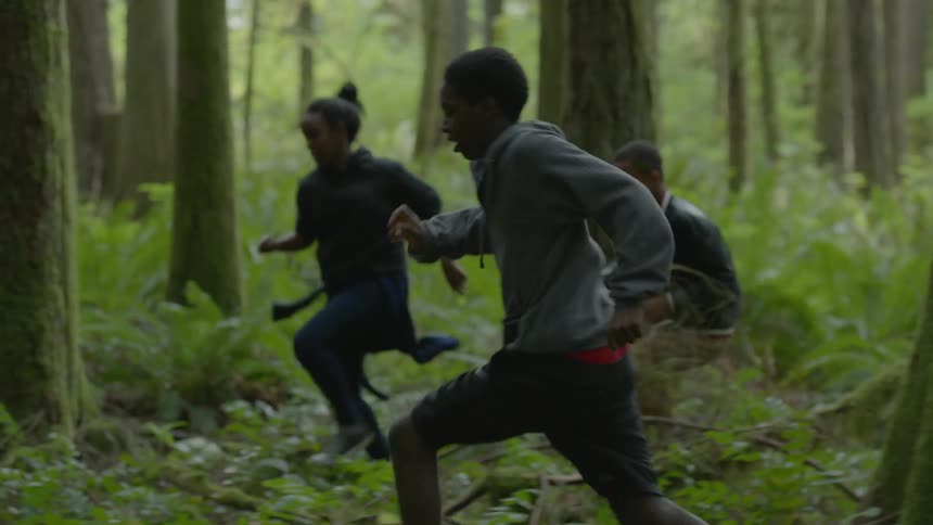 Teenagers running through the woods at daylight
