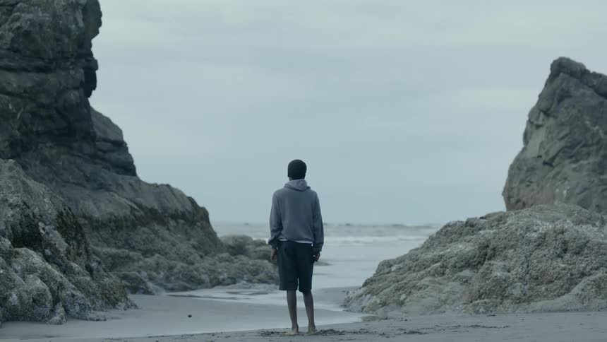 A man stands on the sand watching the ocean