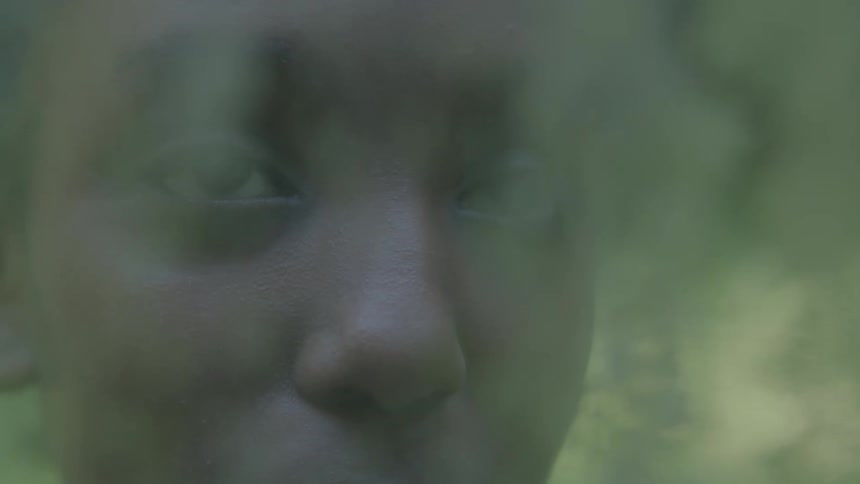 A young woman speaks into the camera with part of her face cut off