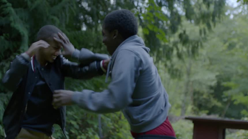 Two young boys fight each other outdoors