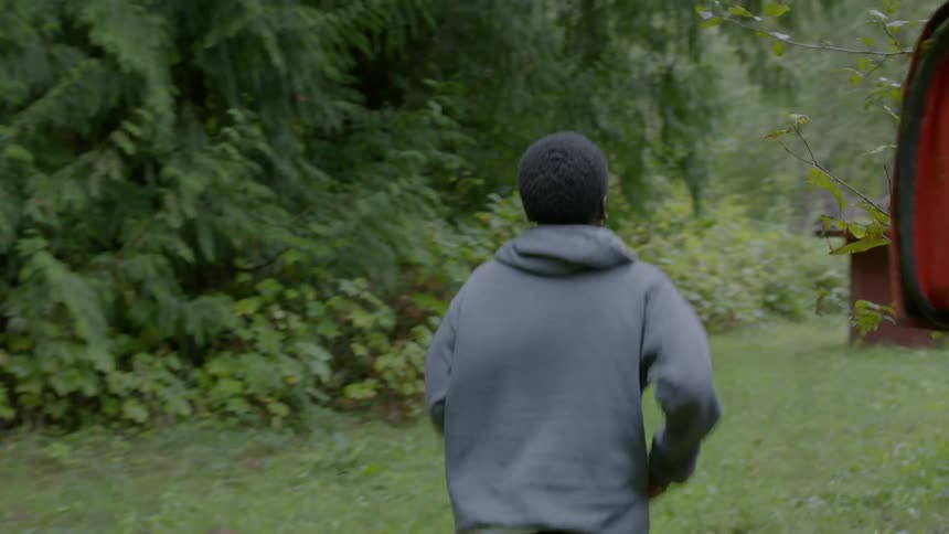 Teenager boy running through abandoned cars near a forest