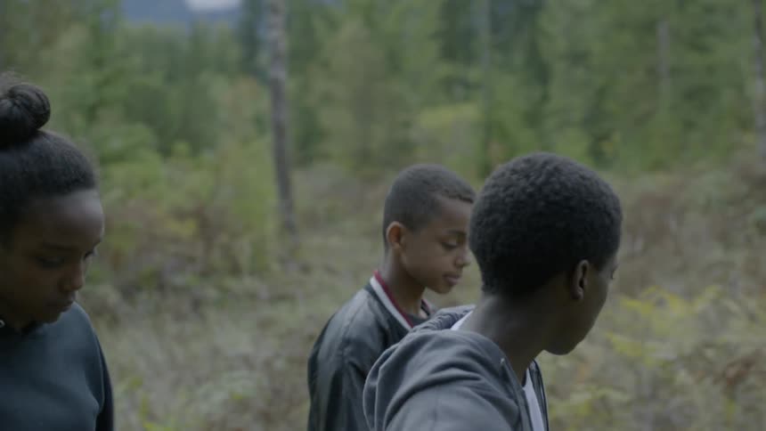 Two boys and a girl walking in a forest