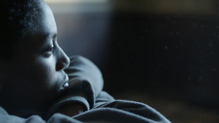 Black man blinks his eyes as he sits still looking straight ahead