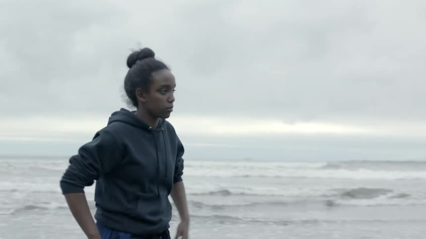 Teenagers walking on the beach next to the ocean on a cold overcast day