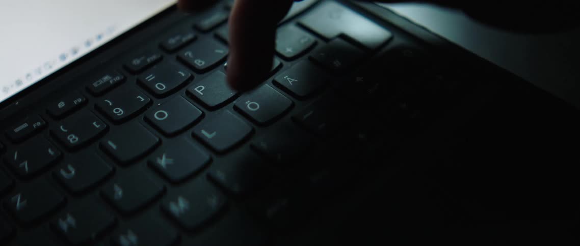 A white person punches several keys on a keyboard