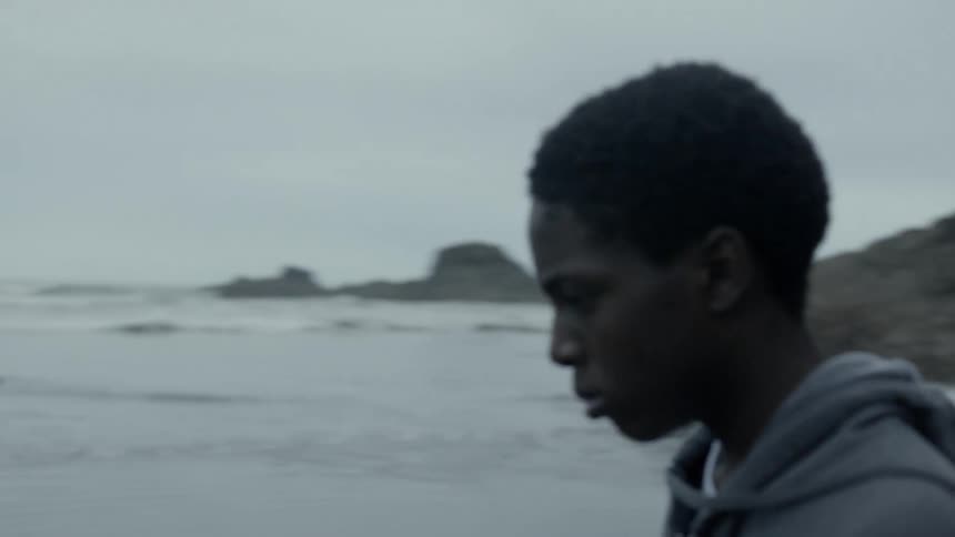 Boys through stone toward the ocean while walking on the beach