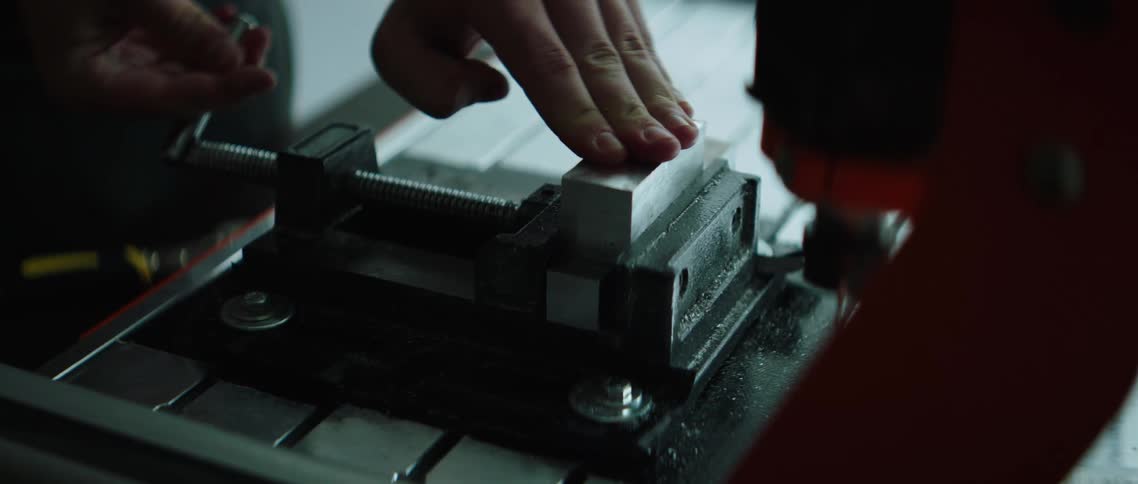 Hands turn and tighten a guide on a tool workbench
