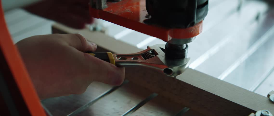 A wrench being used to adjust the chuck of a drill press
