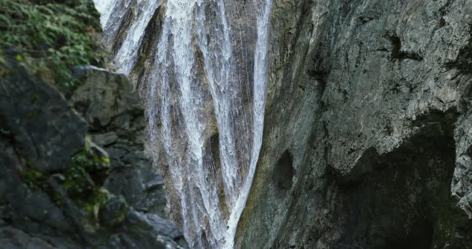 Slow motion waterfall streams over rock wall