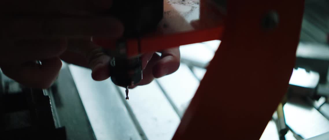 A man screws a drill bit in to a tool