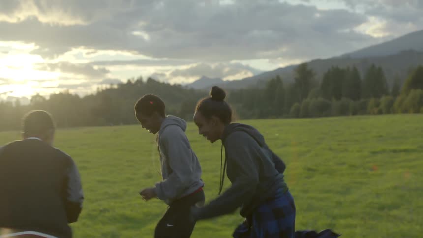 Three teens laugh and shove one another as they run together