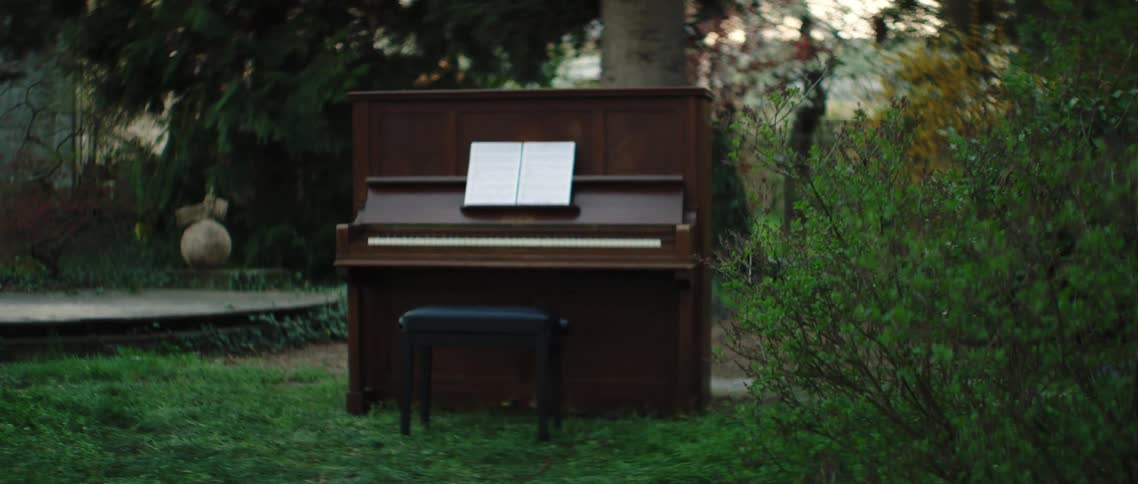 Sheet music sits on a piano near the trees