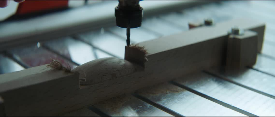 A persons hand rubbing a piece of wood by a drill