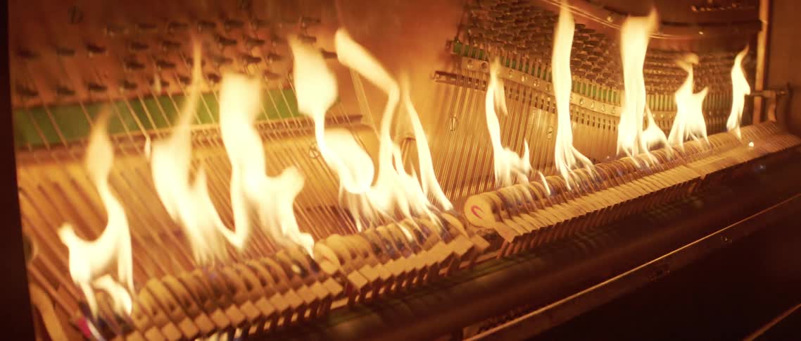 The inside strings and hammers of a musical instrument flame and burn as it is played