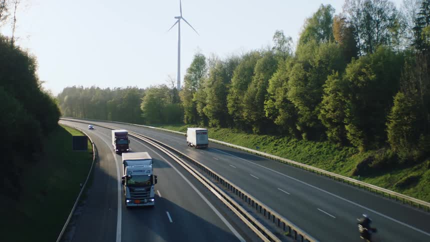 Trucks and other vehicles drive down a divided roadway