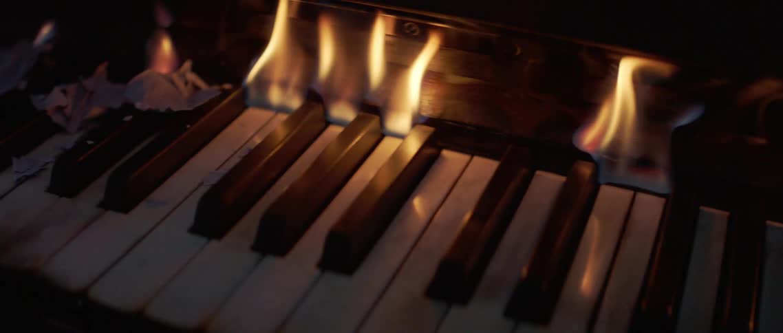 Piano keys melt as flames rise from underneath