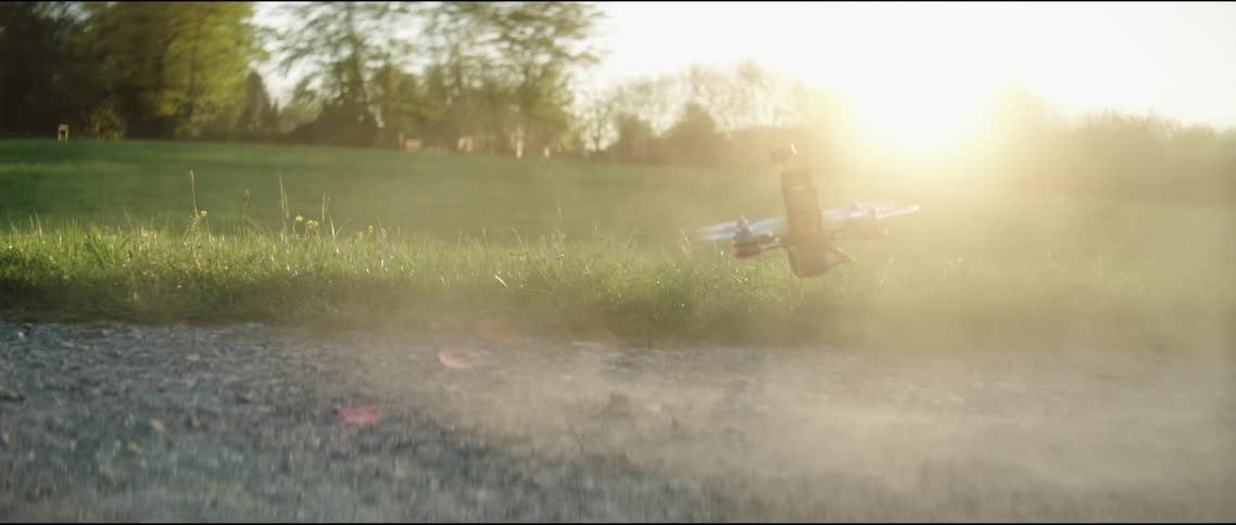 Small drone flies toward camera in field