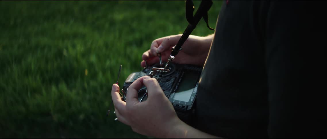 A person standing outdoors operating a large radio control device
