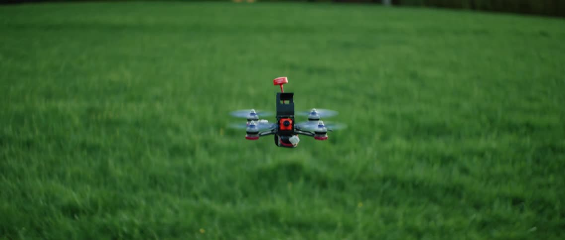 Small drone in flight over field at dawn